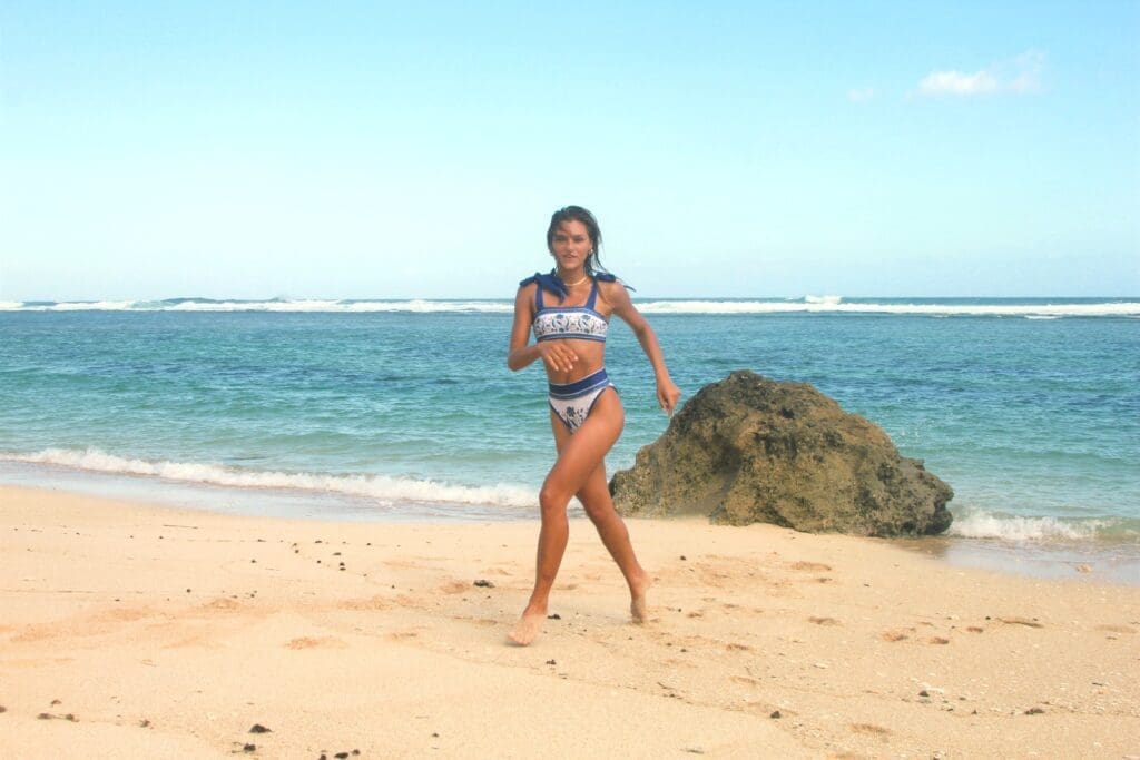 A woman in a bikini is running on the beach